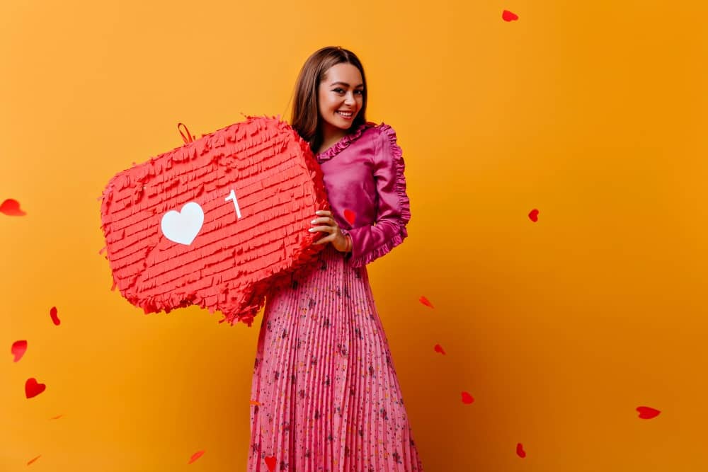 gorgeous-joyful-cheerful-girl-posing-with-red-decorations-her-hands-portrait-brown-haired-woman-pink-outfit-against-wall-confetti-shape-hearts