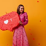 gorgeous-joyful-cheerful-girl-posing-with-red-decorations-her-hands-portrait-brown-haired-woman-pink-outfit-against-wall-confetti-shape-hearts
